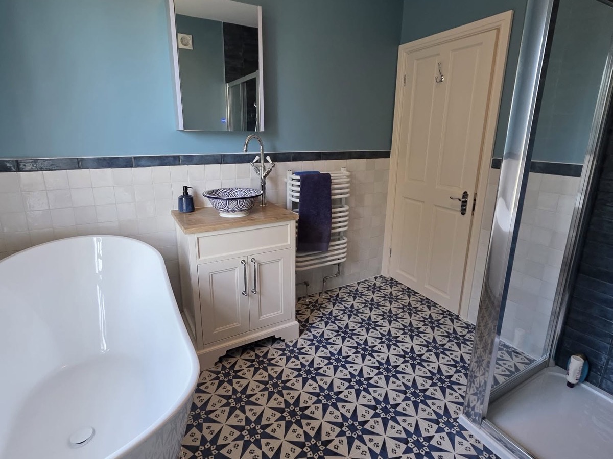 Completed bathroom renovation with a freestanding bath, patterned floor tiles, vanity unit and separate shower enclosure