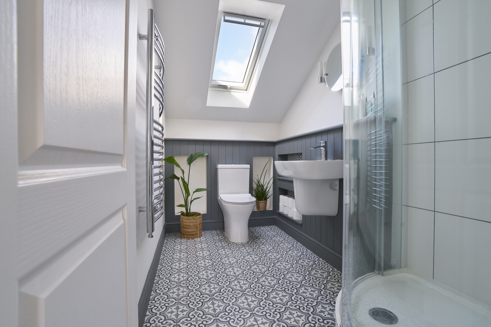 Compact modern shower room with tongue and groove panelling and patterned floor tiles
