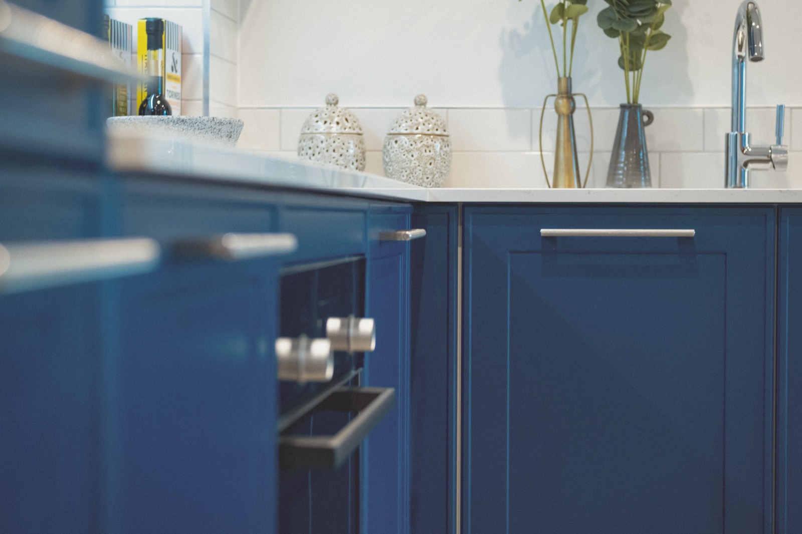Navy shaker kitchen units with a white quartz worktop and brushed steel handles