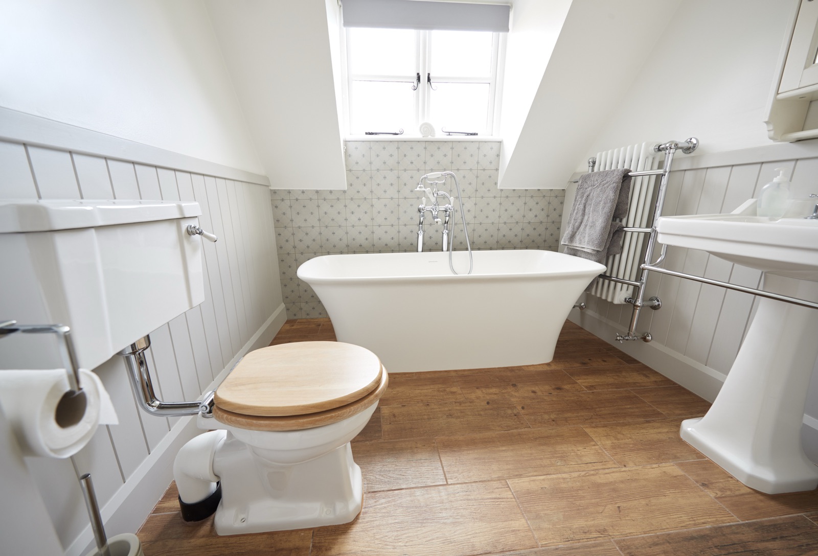 Traditional bathroom with a freestanding bath, panelled walls and wood-effect flooring