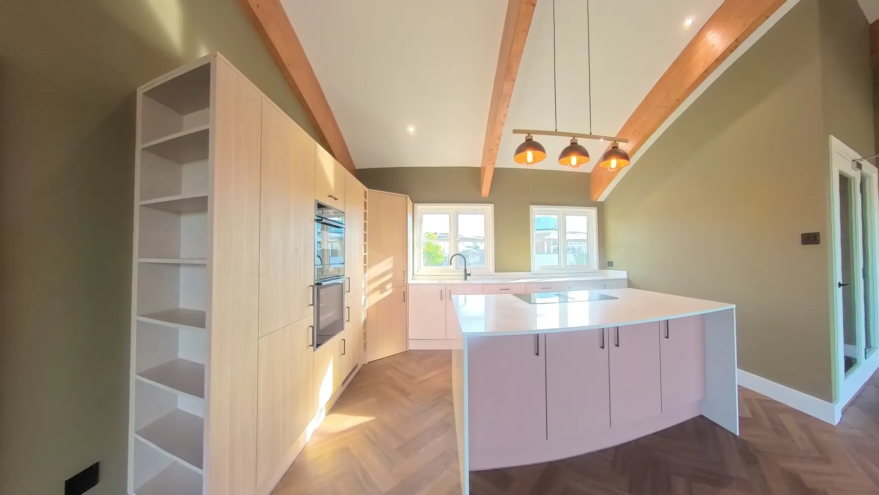 Completed kitchen with a curved island, integrated ovens and herringbone LVT flooring in a full house renovation in Thorpe Hamlet, Norwich